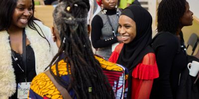 Women with head scarves and uncovered heads greet each other, smiling
