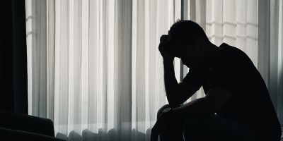 Shadowed image of person with their head in their hands